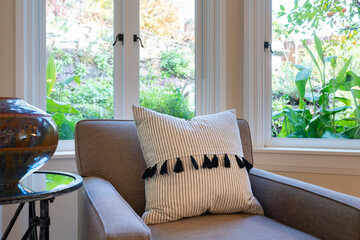 Detail of side chair with large pillow and window view of garden. 