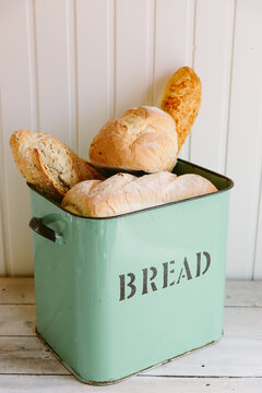 Various types of bread in a vintage bread bin.