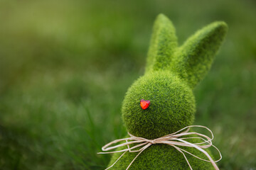 Close up Easter bunny rabbit statuette and basket with easter eggs on the green grass lawn...