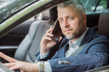 Handsome caucasian businessman driver inside in vehicle and gadget and check mail and talking with partners