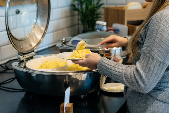 No Face Woman Putting Scrambled Eggs In A Self-service Buffet With Hot Breakfast In The Hotel. Continental Breakfast Concept. Selective Focus, Copy Space.