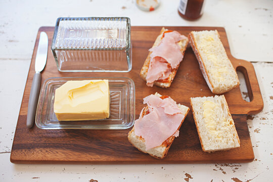 Preparing lunch at home. Baguette with butter, ham, lettuce and tomato