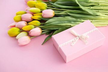 Bouquet of colorful tulips and gift box isolated on pink background. Spring flowers. Greeting card...