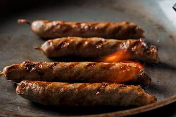 Grilled sausages in a frying pan are fired with a gas burner