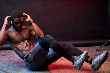 shirtless man do exercises on the floor, intense training isolated on black background