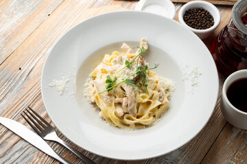 Chicken pasta with creamy sauce and grated parmesan cheese on a wide white plate