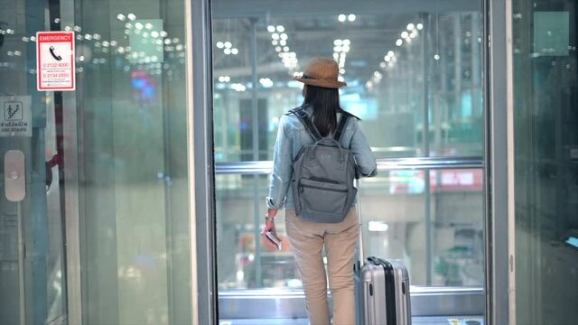 Travelling Woman Walk  Out The Elevator At Airport With Her Rolling Baggage.