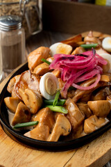Meat and potato stew in a german restaurant in a cast-iron pan, wooden background