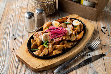 Meat and potato stew in a german restaurant in a cast-iron pan, wooden background
