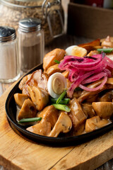 German slow stew with potato, mushrooms and onion, covered with gravy on wooden tray