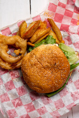 Cheese burger with onion rings and potato fries on white background