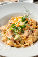 Salmon pasta with capers and creamy sauce in white wide dish