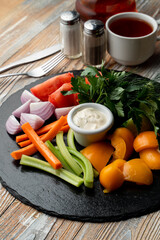 Vegetables platter with tomato, celery, onion and carrot sticks, sauce boat in the centre