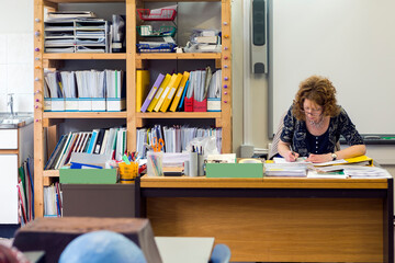 Classroom with teacher sitting behind her desk preparing for her class