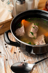 Spicy and warm autumn soup on meat broth, served in rustic pot on a wooden table
