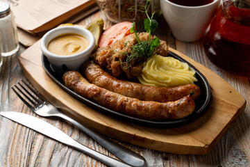 Appetizing roasted german wursts with spicy mustard and fluffy mashed potato, german pub photo