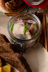 Norwegian salted herring, pickled in a traditional marinade with rye bread and baked potato, close up, mouthwatering magazine photo