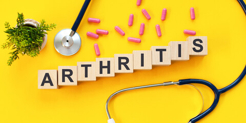 ARTHRITIS word written on wooden blocks and stethoscope on light yellow background
