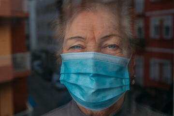 old woman or grandmother with mask at the window