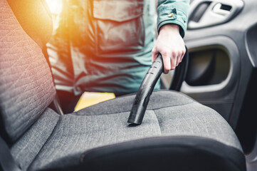 Woman hoovering a car cabin. Vacuum cleaning car seats interior..