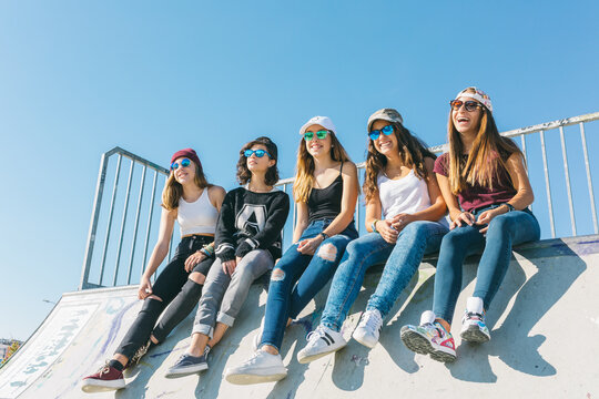 Five girls sit in a skateboard park.