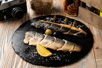 Whole trout, slowly smoked with lemon, on a black plate, top view