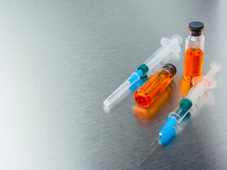 Selective focus. Close-up shot of injection syringes and ampoules with orange coronavirus vaccine...