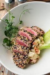 Raw roasted tuna fillet with sesame coat and sprouts, close appetizing photo