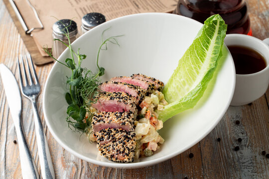 Raw roasted tuna fillet with sesame coat and sprouts, close appetizing photo