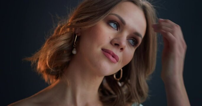 Caucasian woman's portrait. Young woman with make up looks at the camera and touches her hair