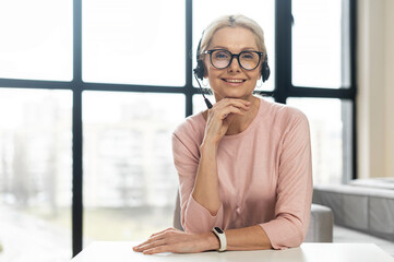 Portrait of a charming smiling elegant mature blonde woman or middle-aged customer service...