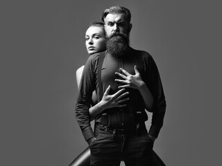 Fototapeta na wymiar Fashion couple. Pretty girl embraces handsome man hipster with beard and moustache fashion couple on grey background.