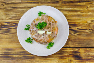 Meat aspic in a plate on a wooden table. Top view. Traditional russian dish