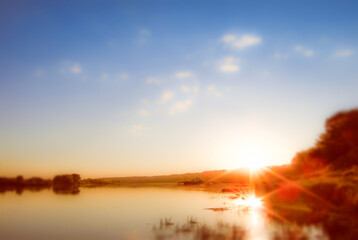 Landscape with a ship and blurred sunset over the river 