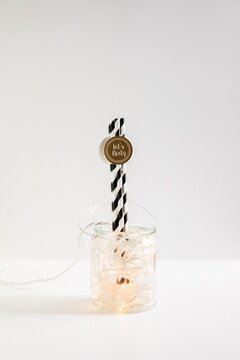 Glass jar filled with lights and straws with text ""lets party""