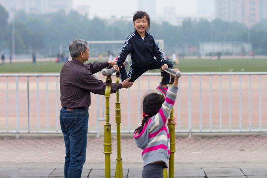 Senior man help her little Granddaughter on parallel bars