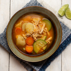 Chicken soup with rice and vegetables on white background
