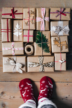 Feet with warm winter socks standing in front of Christmas gifts