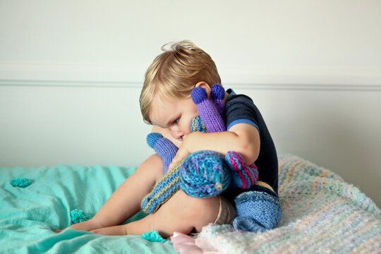 Blonde Toddler Boy Hugging Handmade Dolls