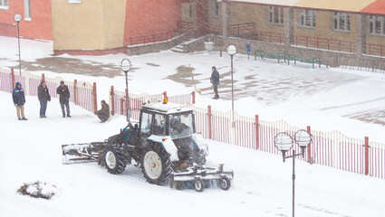 Tractor removing snow from the road during a blizzard