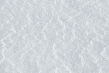 Background of snow with a light texture of wind waves. 