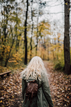 Backside view of a blonde woman with backpack in nature