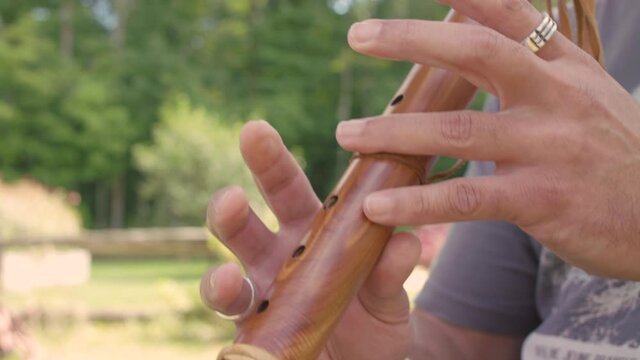Man playing the flute in nature. The musician performs music in the fresh air. The close-up of musical instrument with nature in the background