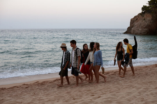Group of teenagers walking on a mediterranean beach after sunset