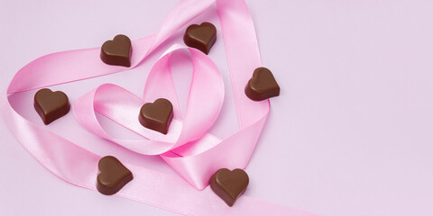 Dark chocolate and pink heart-shaped ribbon. Sweet gifts for Valentine's Day. Selective focus, copy space.