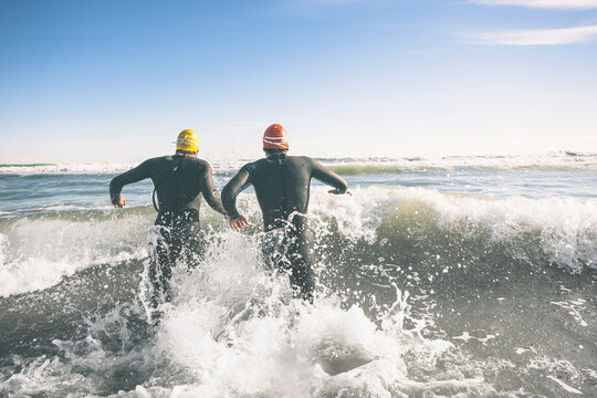 Two triathletes running to the water on triathlon race.
