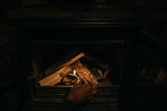 Man's hand using match to light fire logs
