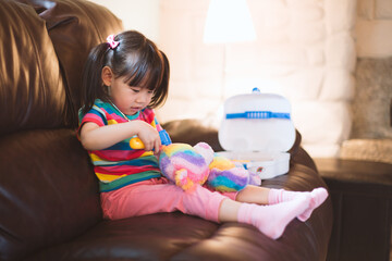 young girl pretend play as doctor looking after her bear paient  in the living room