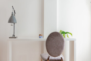 Minimalist and modern room with a white table, a gray chair and a lamp
