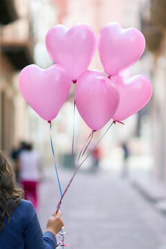 Young woman holding pink heart shaped balloons